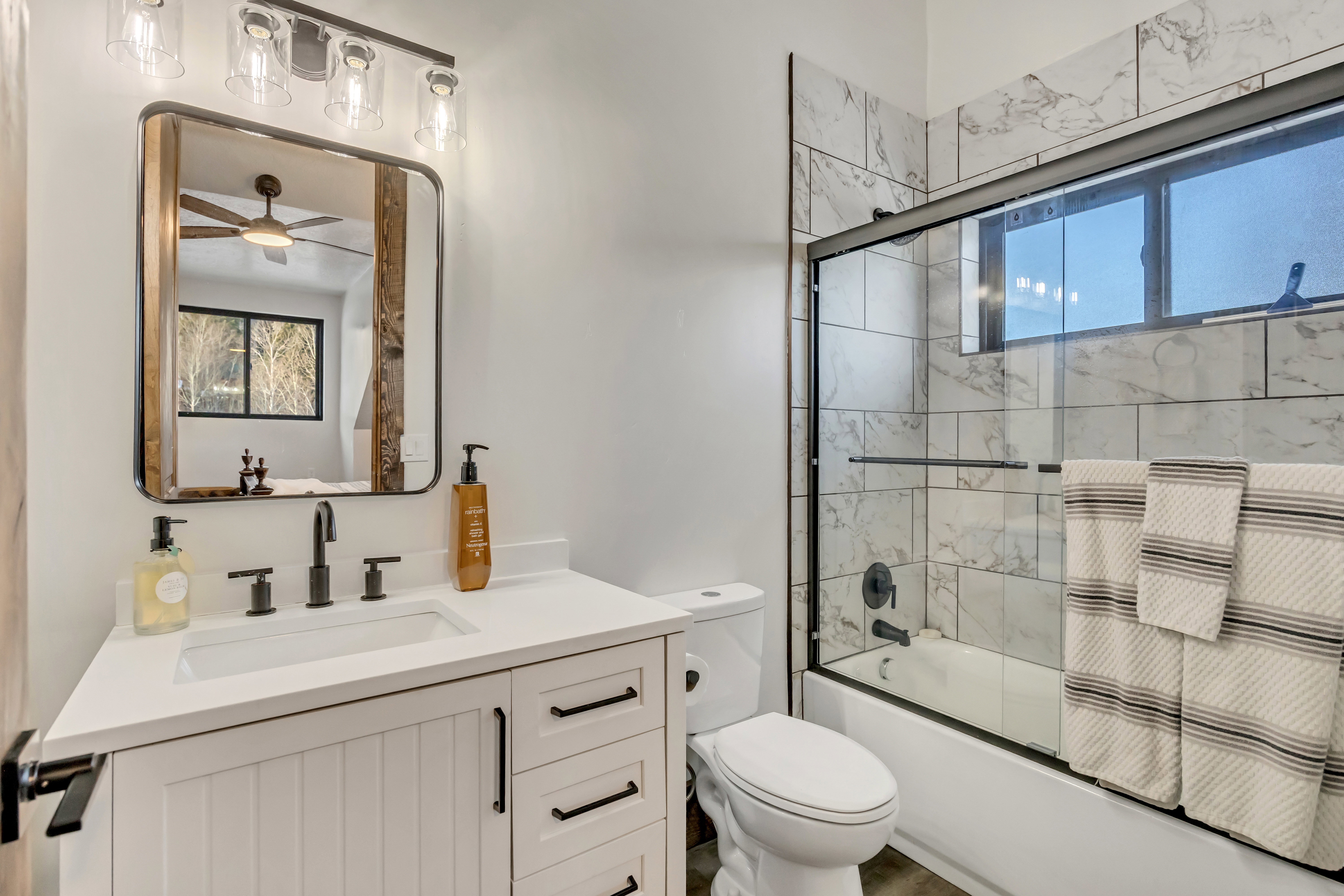Full bathroom with combined bath / shower with glass door, vanity, and ceiling fan