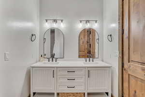Full bathroom with double vanity and baseboards