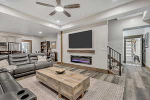 Living area with wood finished floors, ceiling fan, a glass covered fireplace, and recessed lighting