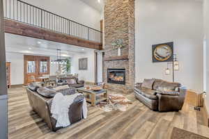 Living area with a towering ceiling, light wood-style flooring, a fireplace, and recessed lighting
