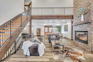 Living room featuring a high ceiling, light wood-type flooring, a stone fireplace, and recessed lighting
