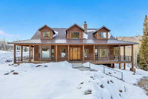 Chalet / cabin featuring covered porch, a chimney, and a metal roof