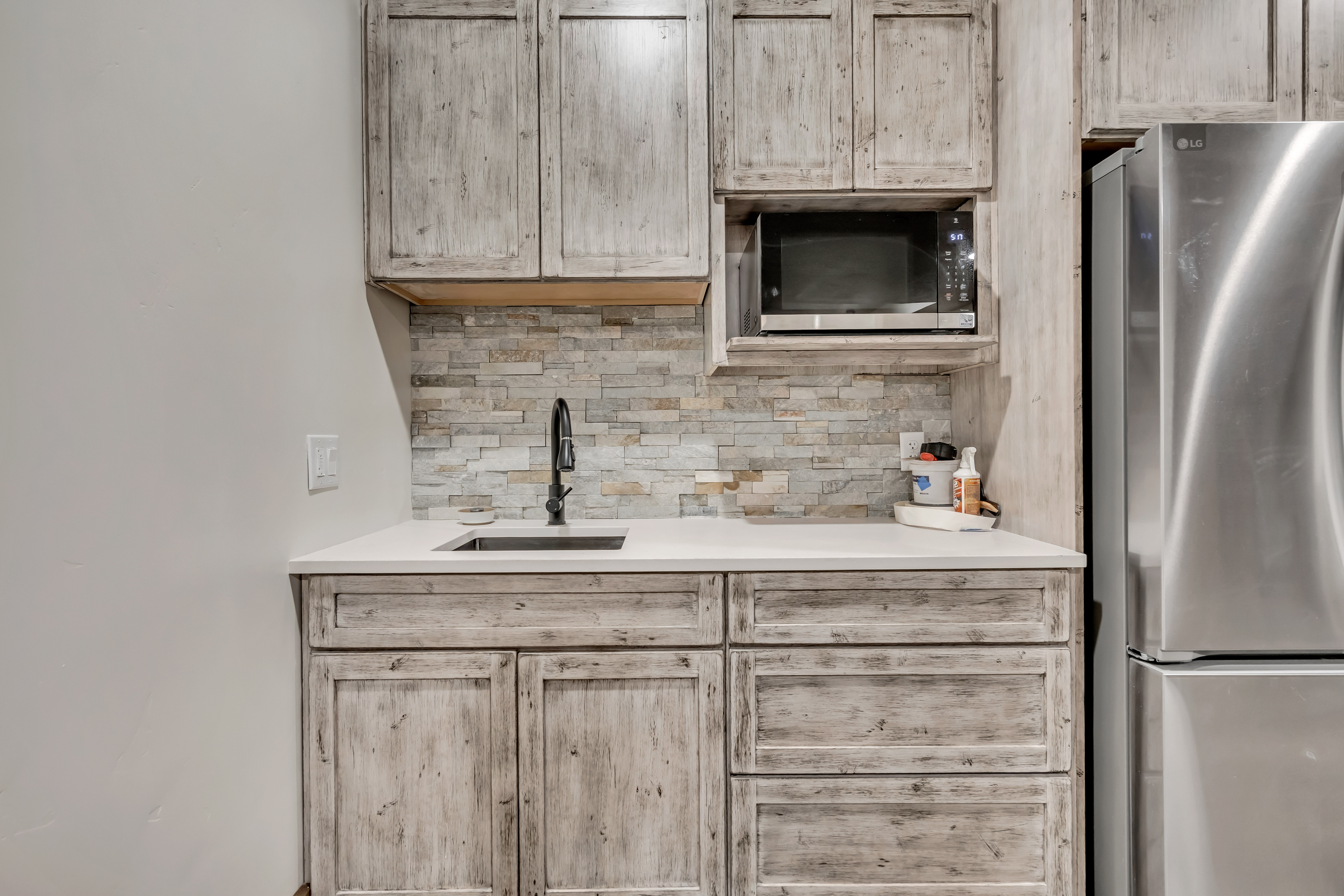 Kitchen featuring appliances with stainless steel finishes, light brown cabinetry, decorative backsplash, and light stone countertops