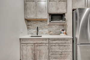 Kitchen featuring appliances with stainless steel finishes, light brown cabinetry, decorative backsplash, and light stone countertops