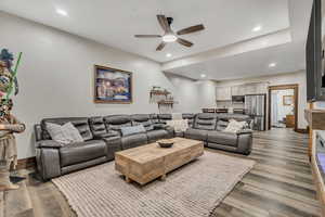 Living room with wood finished floors, ceiling fan, recessed lighting, and a glass covered fireplace