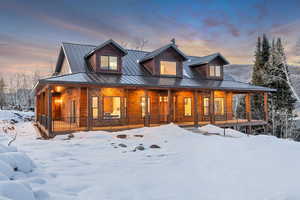 View of front of home featuring faux log siding, a porch, and a metal roof