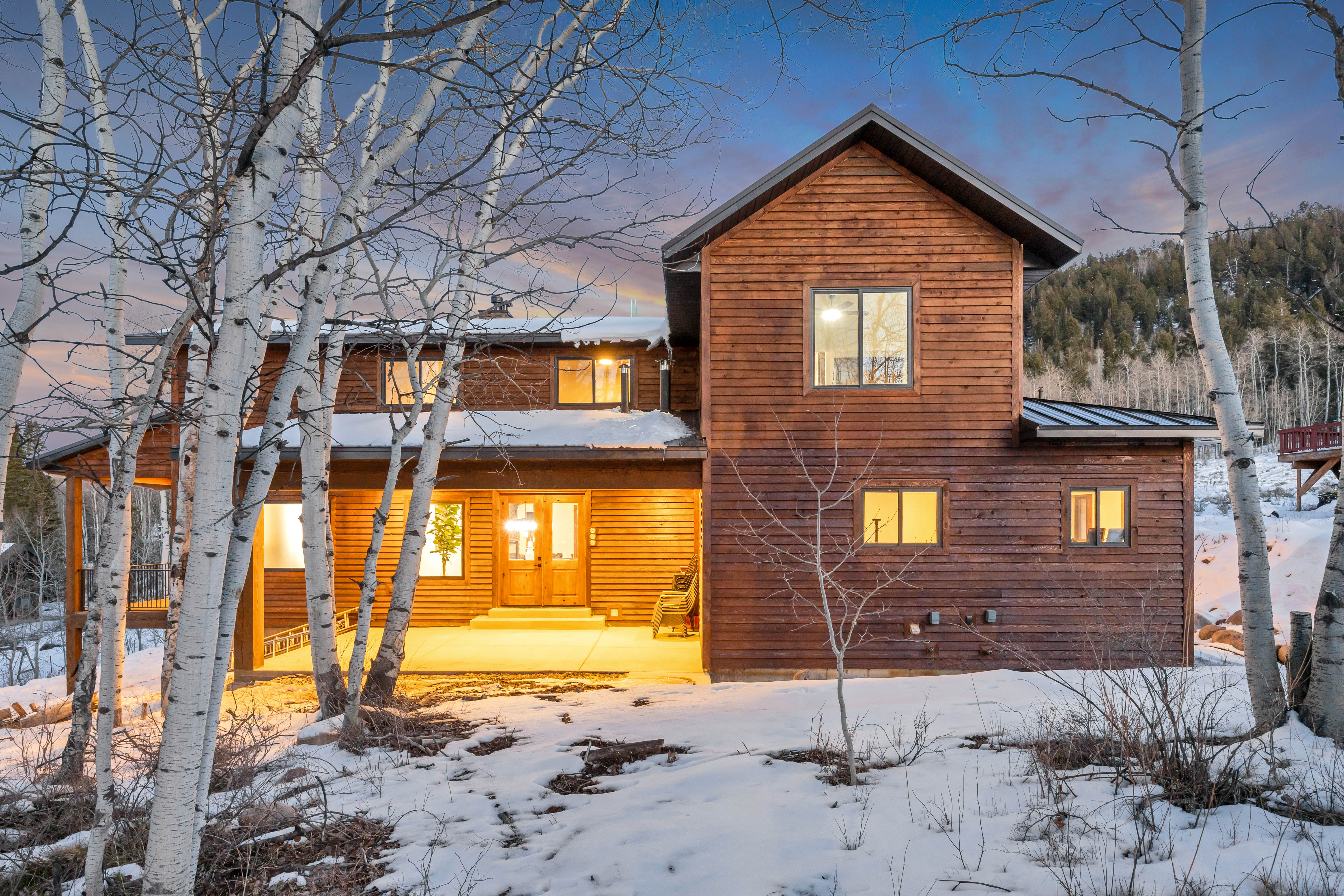 Snow covered house featuring a porch and a metal roof