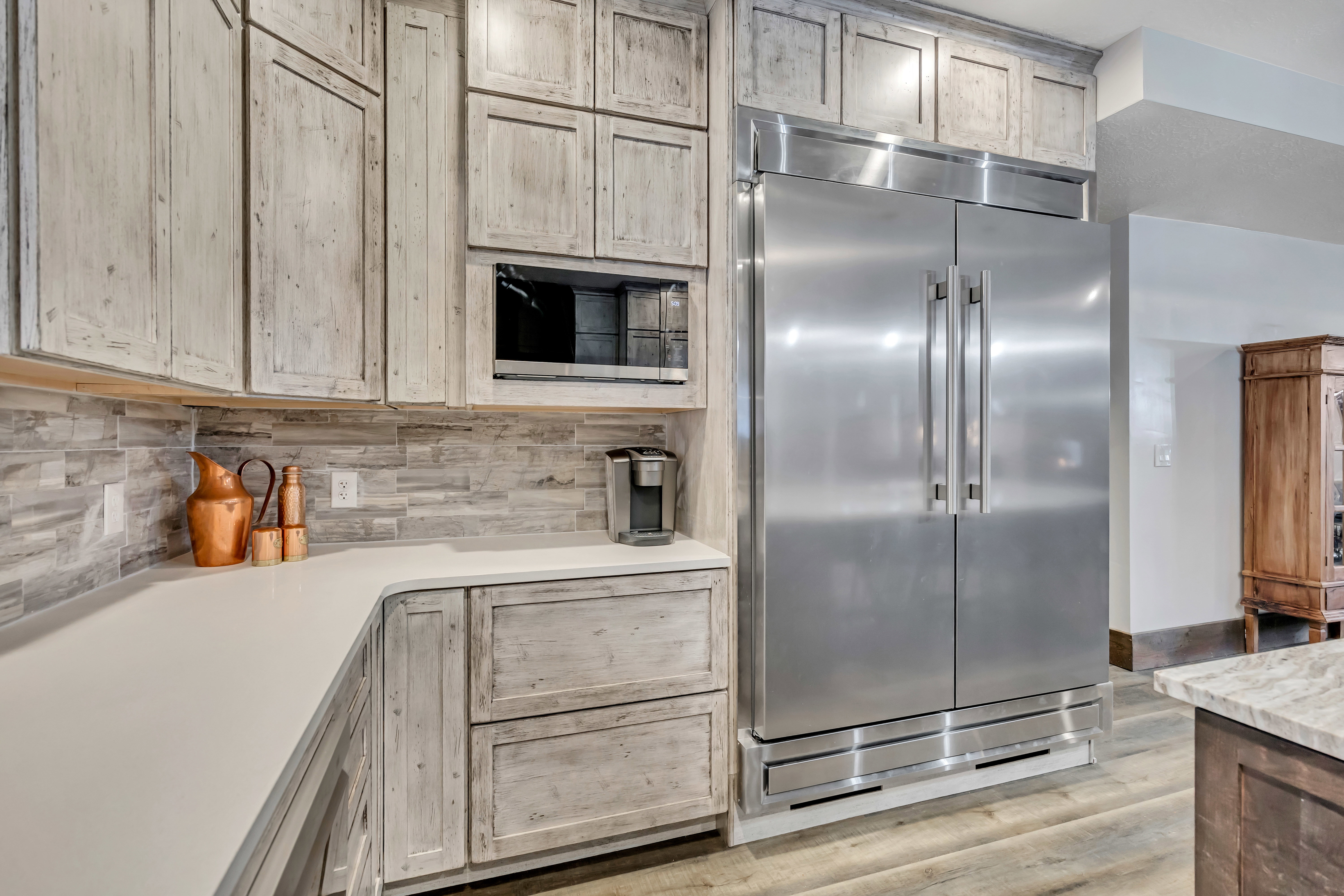 Kitchen featuring appliances with stainless steel finishes, light brown cabinets, light wood-style floors, and backsplash