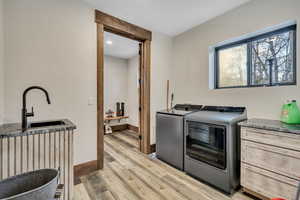 Laundry area with light wood-style flooring, washing machine and clothes dryer, and recessed lighting