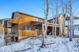Snow covered rear of property featuring a patio area
