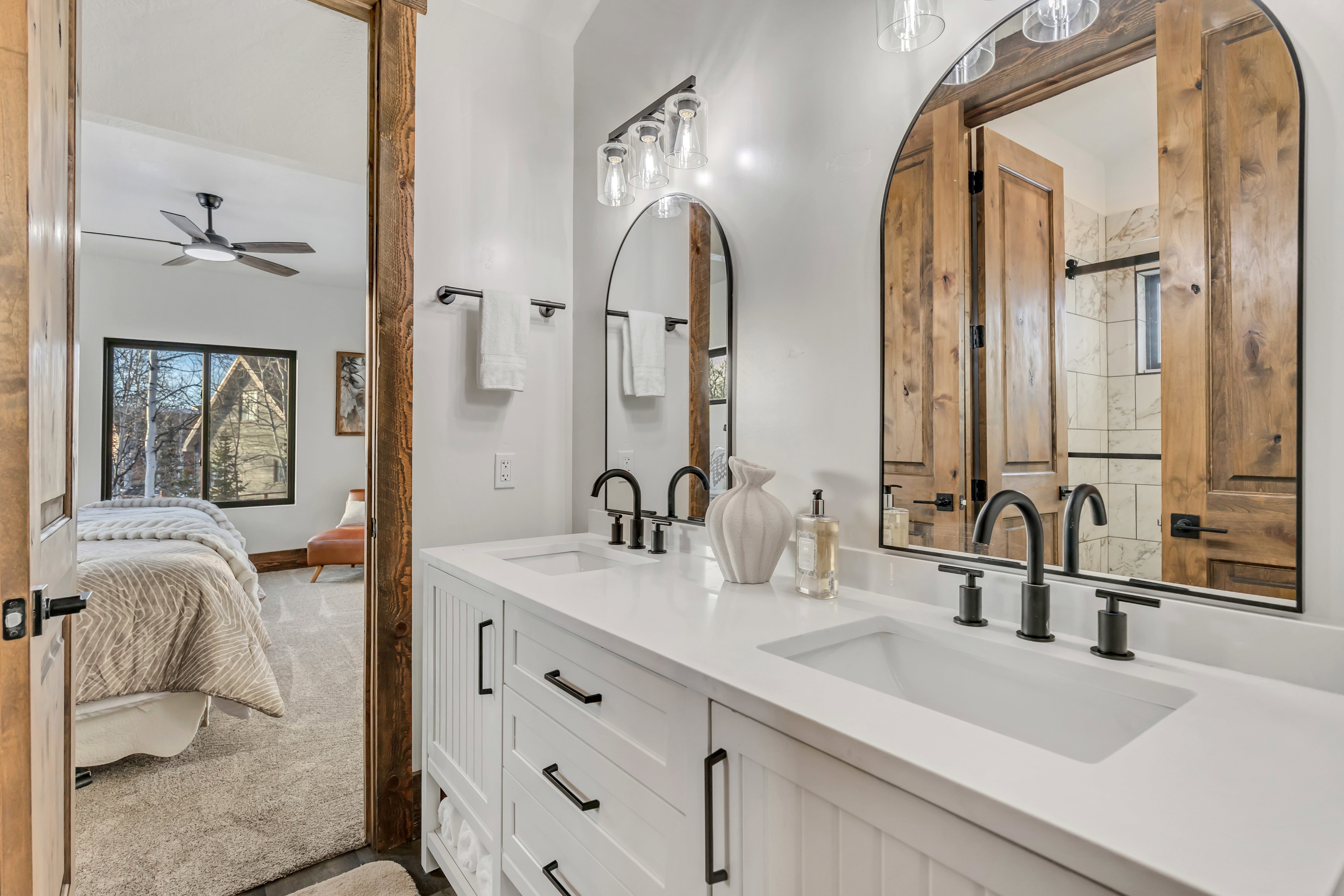 Full bathroom with double vanity, ensuite bath, ceiling fan, dark carpet, and a shower
