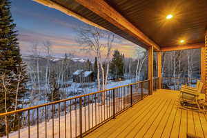 Snow covered deck featuring a mountain view and view of scattered trees
