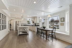 Dining area with light wood-style floors, a barn door, a wooden ceiling with exposed beams, and recessed lighting