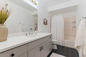 Bathroom featuring shower / tub combo, vanity, and dark tile patterned flooring