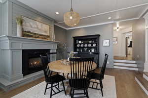 Dining room featuring hardwood / wood-style floors, recessed lighting, a lit fireplace, and crown molding