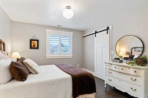 Bedroom featuring a barn door and dark wood-type flooring