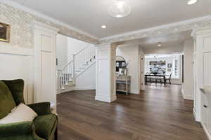 Living area with dark wood-style flooring, stairway, ornamental molding, recessed lighting, and decorative columns