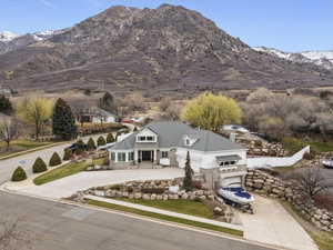 View of front of house with stone siding, a mountain view, a garage, and concrete driveway