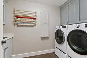Laundry area with cabinet space, radiator, washer and dryer, and dark wood-style flooring