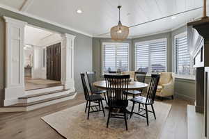 Dining area featuring light wood-type flooring, recessed lighting, decorative columns, and crown molding