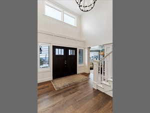 Entryway with plenty of natural light, dark wood-style floors, a towering ceiling, and stairway