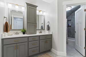 Bathroom featuring double vanity, shower / bathtub combination with curtain, and light marble finish flooring