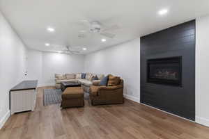 Living room featuring ceiling fan, a fireplace, recessed lighting, and light wood-style floors