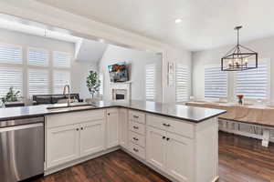 Kitchen featuring dishwasher, open floor plan, white cabinets, a fireplace, and dark wood-style flooring