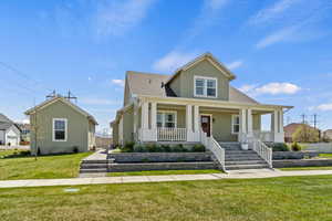 View of front of property featuring a front yard, a porch, and a shingled roof