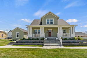 Bungalow with a porch, a front yard, and roof with shingles