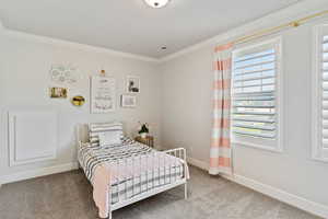 Bedroom with light colored carpet and ornamental molding