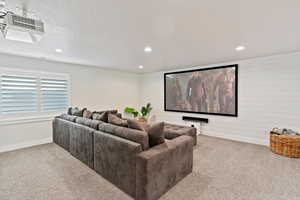 Carpeted cinema room with recessed lighting, wood walls, and a textured ceiling