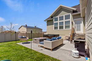 Fenced backyard featuring a patio area, grilling area, and an outdoor living space with a fire pit