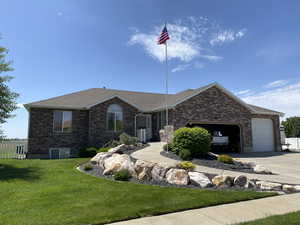 Ranch-style house featuring brick siding, roof with shingles, concrete driveway, and an attached garage