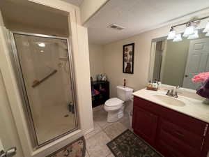 Full bath with a shower stall, vanity, a textured ceiling, and light tile patterned floors