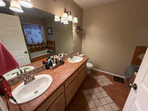 Full bath with a bath, dark tile patterned flooring, double vanity, and a shower