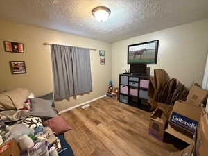 Bedroom with a textured ceiling and hardwood / wood-style floors