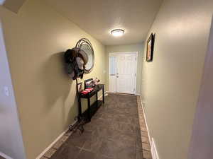 Doorway to outside featuring a textured ceiling and baseboards