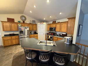 Kitchen with dark countertops, brown cabinetry, stainless steel appliances, a textured ceiling, and a peninsula