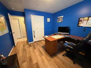 Office space featuring light wood-style flooring and a textured ceiling