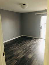 Spare room with dark wood-style flooring