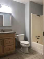 Bathroom with vanity,  shower combination, light tile patterned floors, and a textured ceiling