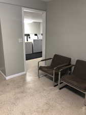 Sitting room featuring dark aggregate flooring and baseboards