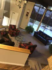 Carpeted living room with a chandelier and baseboards