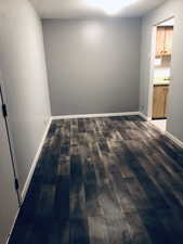 Empty room featuring dark wood finished floors and baseboards