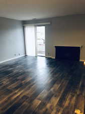 Unfurnished living room featuring dark wood finished floors and baseboards