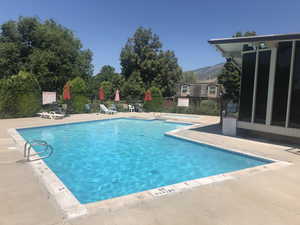 Community pool featuring a patio, a hot tub, and a mountain view