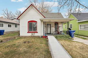 Bungalow-style home with covered porch, brick siding, a front lawn, and a shingled roof