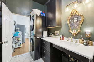 Laundry area with stacked washer and clothes dryer and light tile patterned floors