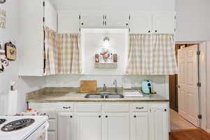 Kitchen with white cabinetry and light stone countertops